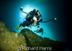 Photographers. Divers swimming into a sea cave in the Poo... by Richard Harris 
